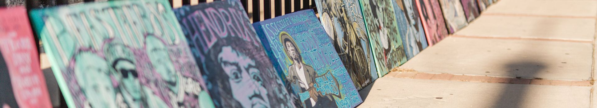 image of paintings leaning on fence